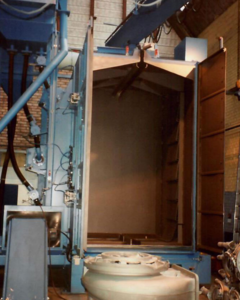 Hängebahnstrahlanlage mit Schwenkkran und vorgeschaltetem Schnecken-Gitterboden zum Ausleeren schöpfender Werkstücke